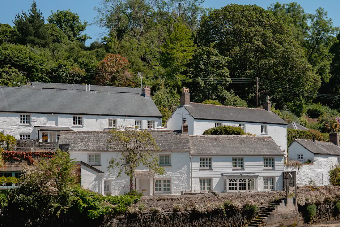 Row of whitewashed cottages beside the calm water of the creek