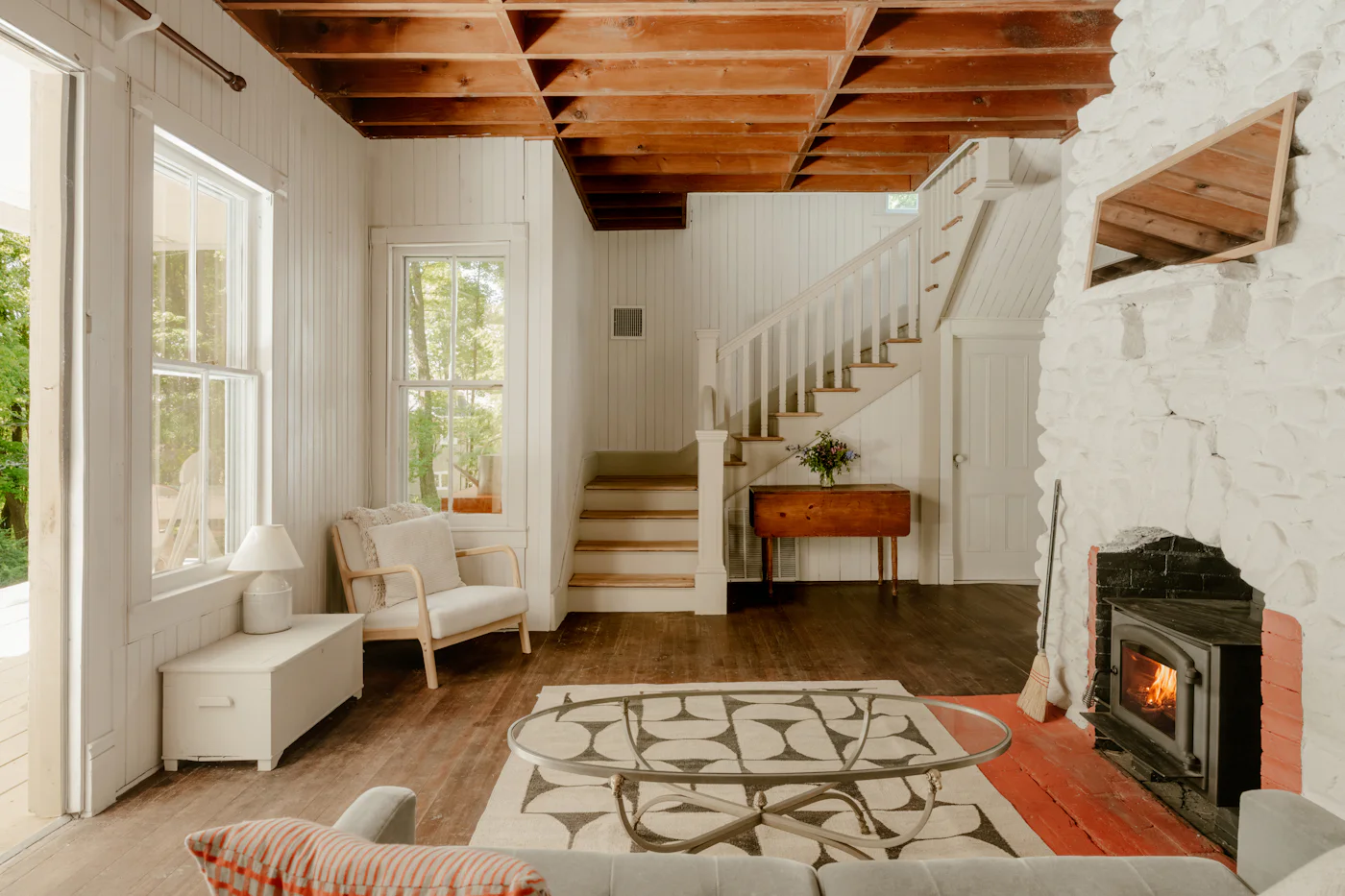 Bright living room with a fireplace, wooden ceiling and a staircase